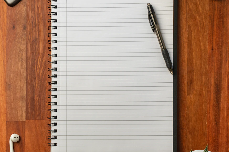 Black pen resting on an open white notebook