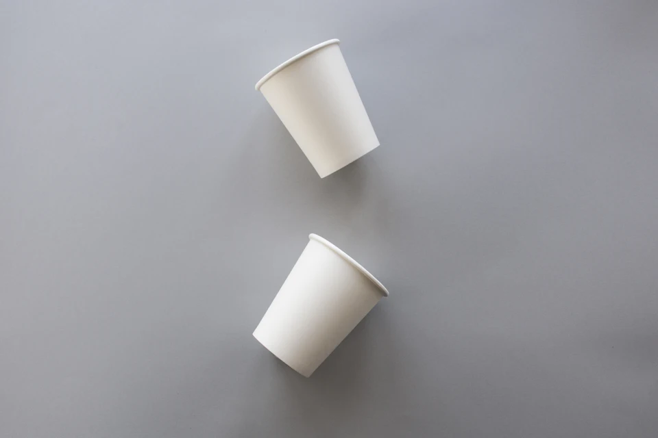 Two white paper cups on a grey surface